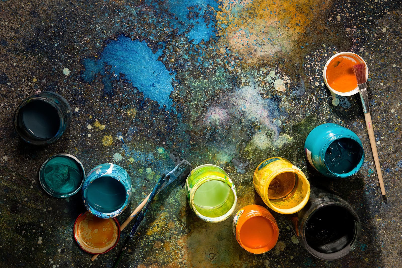 top view of colored paints in jars on the floor